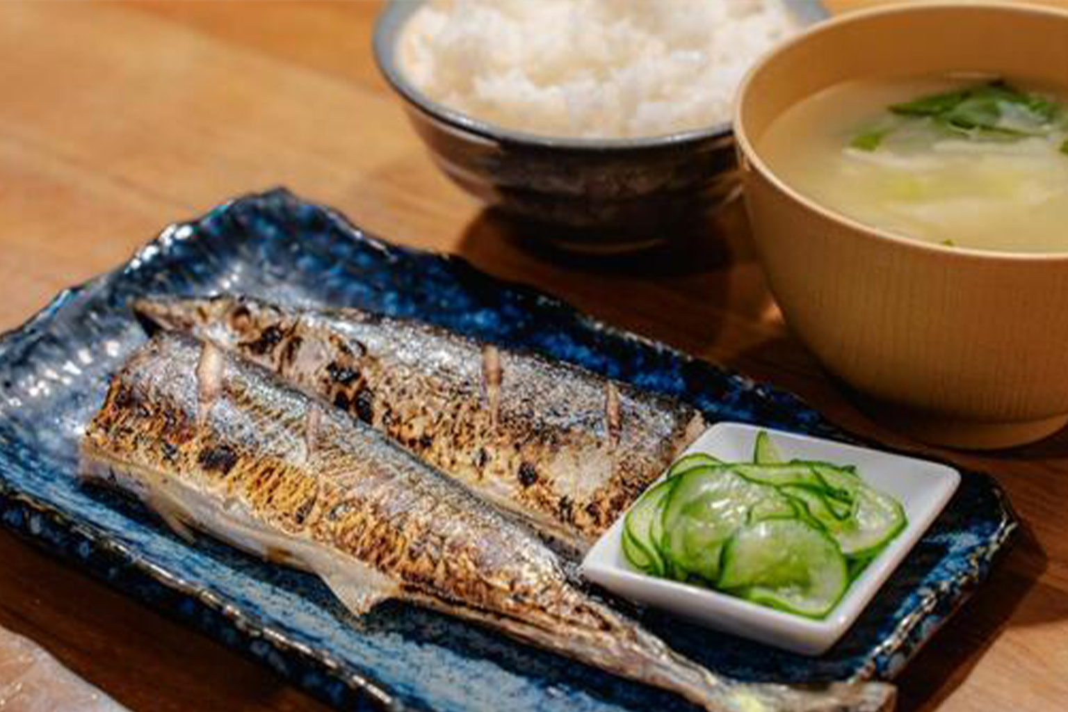 焼き秋刀魚とご飯・味噌汁・きゅうりの漬物が並ぶ和定食