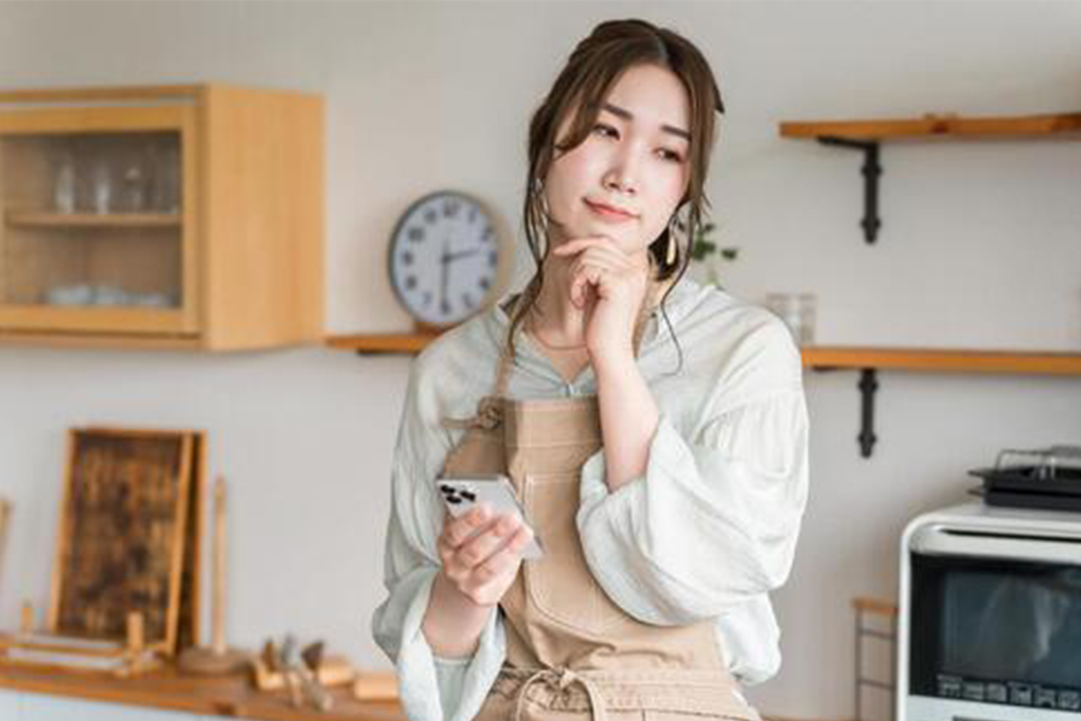 家計管理に悩みながらスマホを見る主婦のイメージ