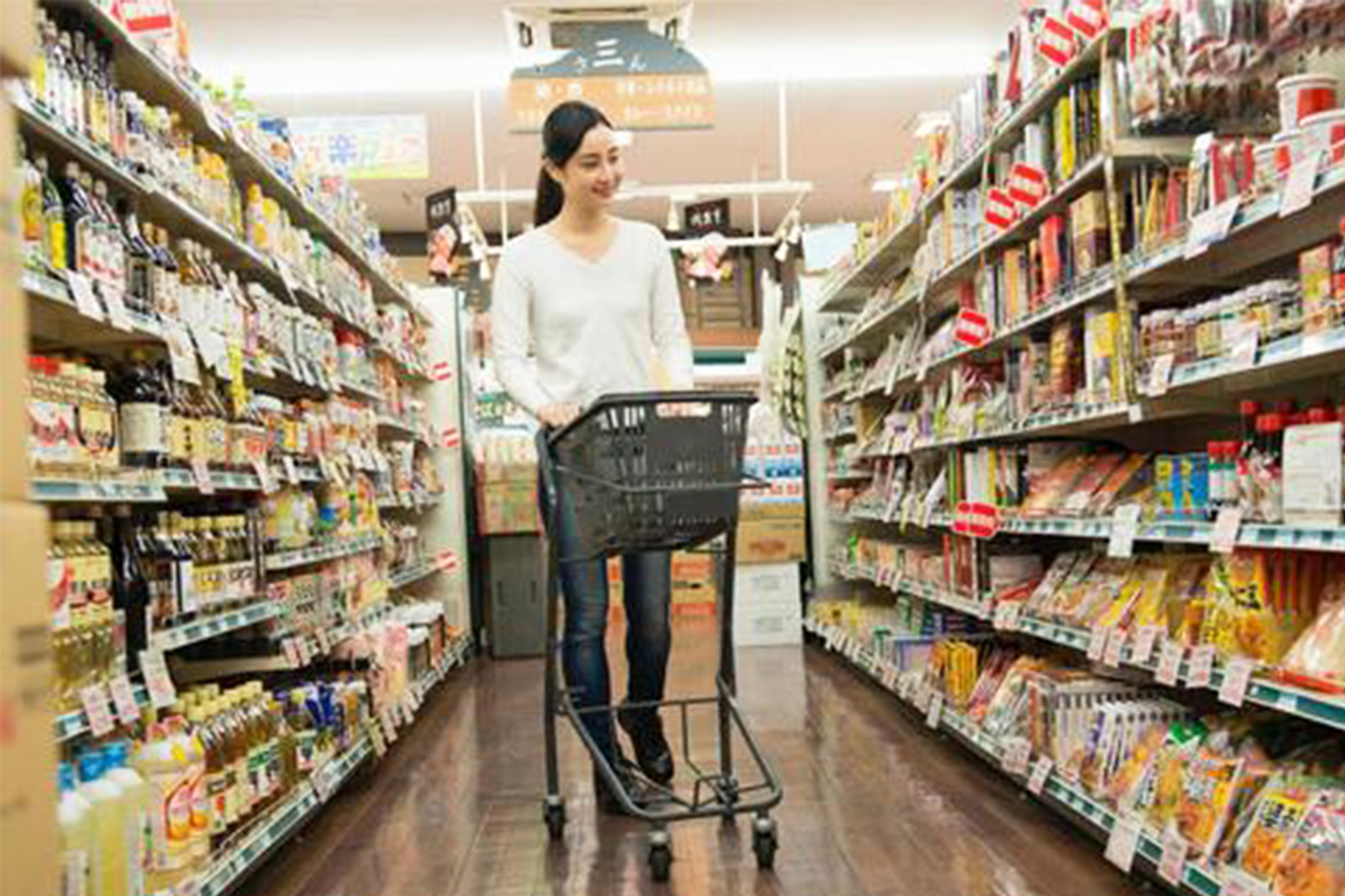 スーパーでカートを押しながら食費節約の買い物をする女性